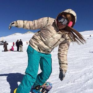 Young woman snowboarding in Tochal, Iran